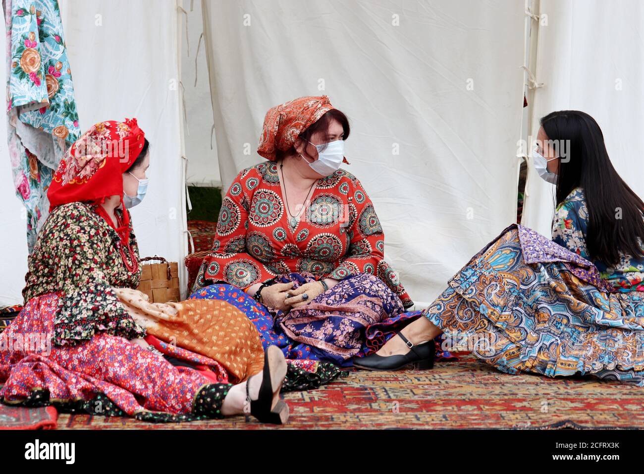 Les femmes roms dans des masques de visage assis dans le camp tzigane au festival historique. Sécurité des événements de masse pendant le coronavirus Banque D'Images