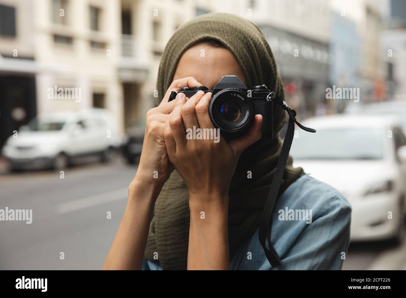 Femme en hijab prenant des photos à l'aide d'un appareil photo numérique sur le rue Banque D'Images