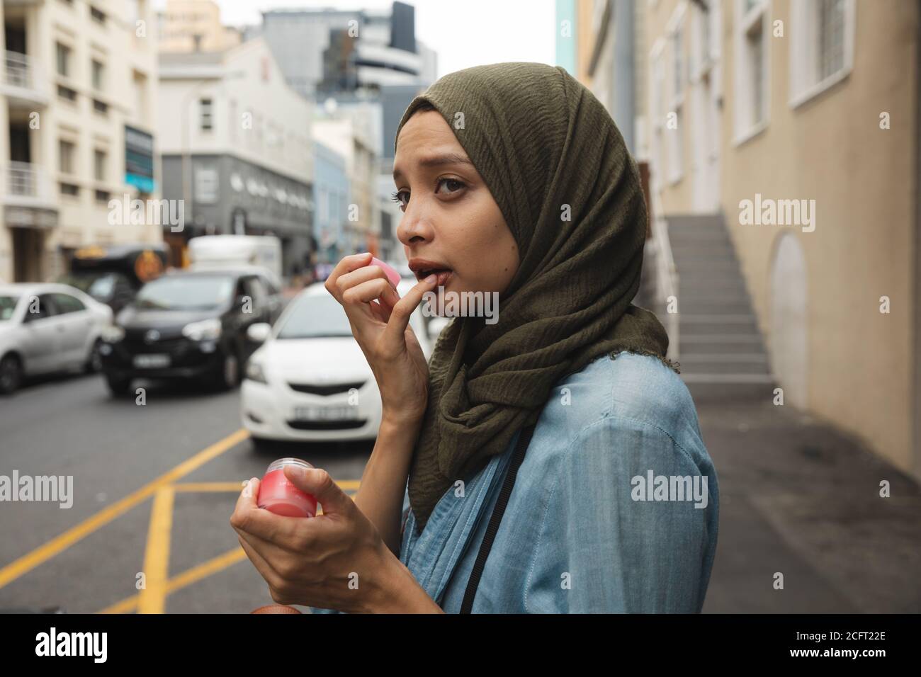 Femme dans hijab appliquant le baume de la lèvre sur la rue Banque D'Images Femme dans hijab appliquant le baume de la lèvre sur la rue Banque D'Images