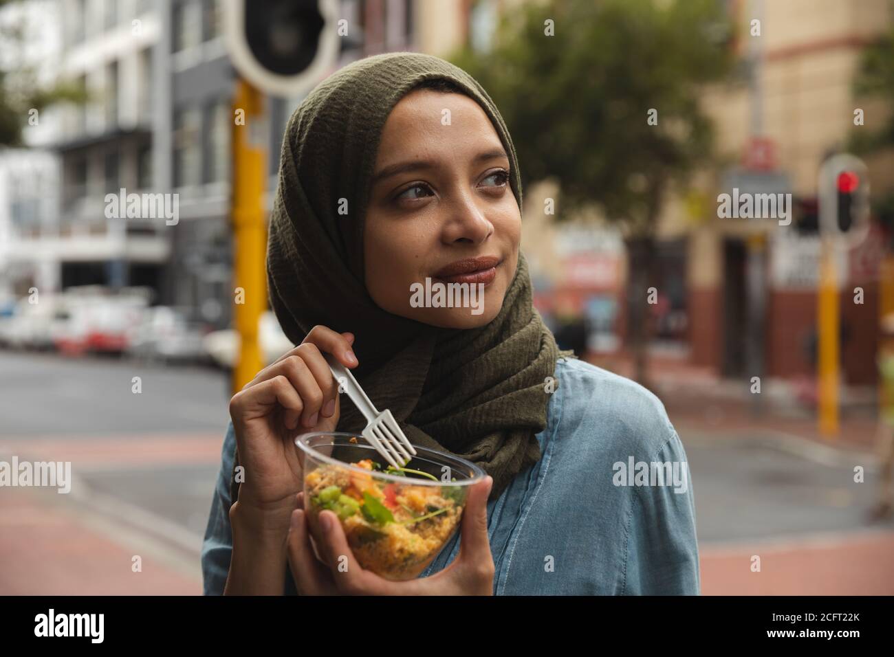 Femme en hijab prenant un en-cas dans la rue Banque D'Images Femme en hijab prenant un en-cas dans la rue Banque D'Images