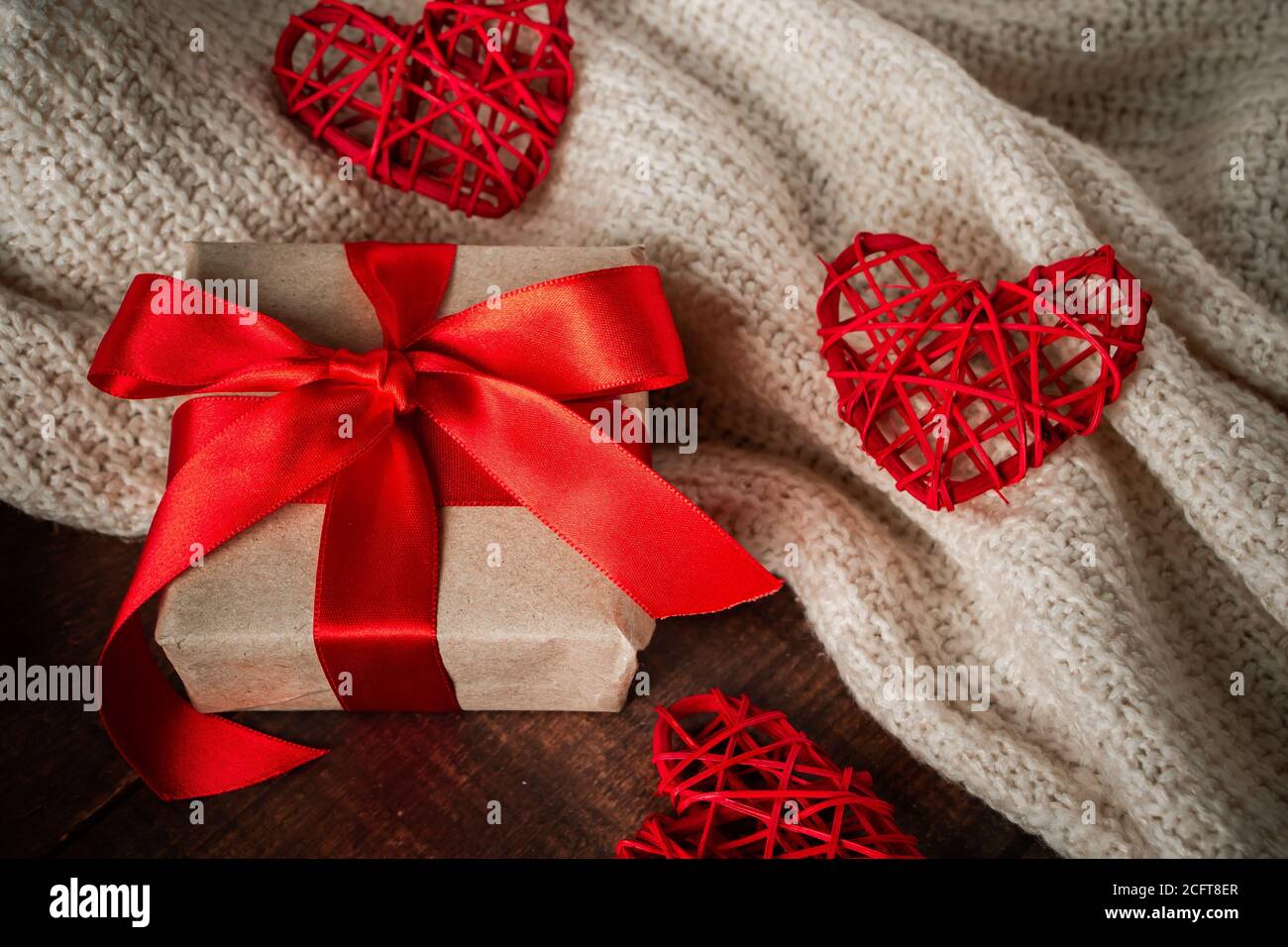 Surprise de la Saint-Valentin en boîte avec ruban rouge. Cadeau pour les  amoureux sur fond de coeurs faits à la main et d'un pull blanc Photo Stock  - Alamy