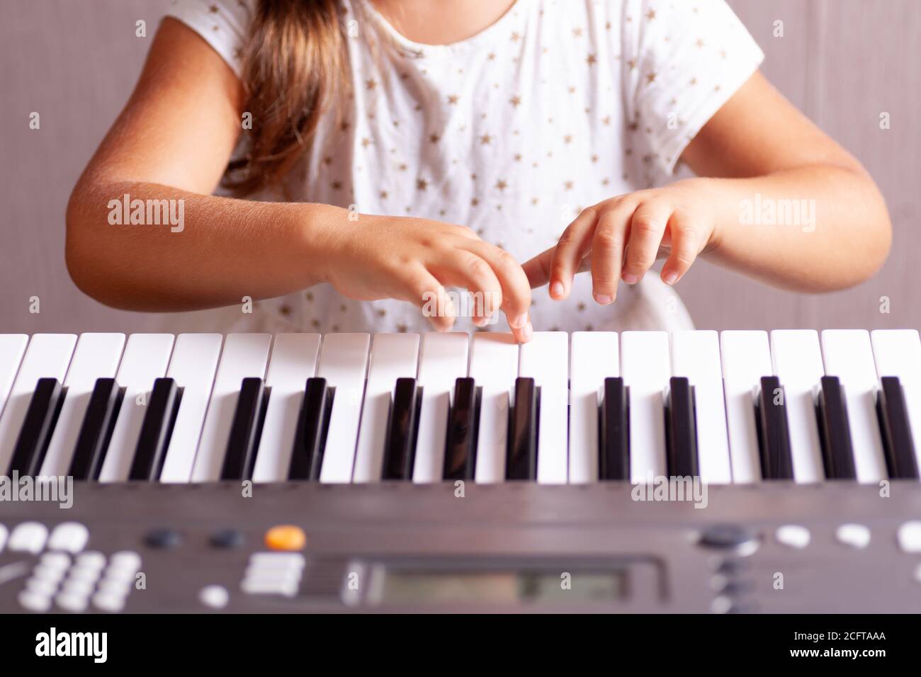 doigts d'une fille dans une robe blanche jouant les clés d'un piano électronique, synthétiseur, gros plan Banque D'Images