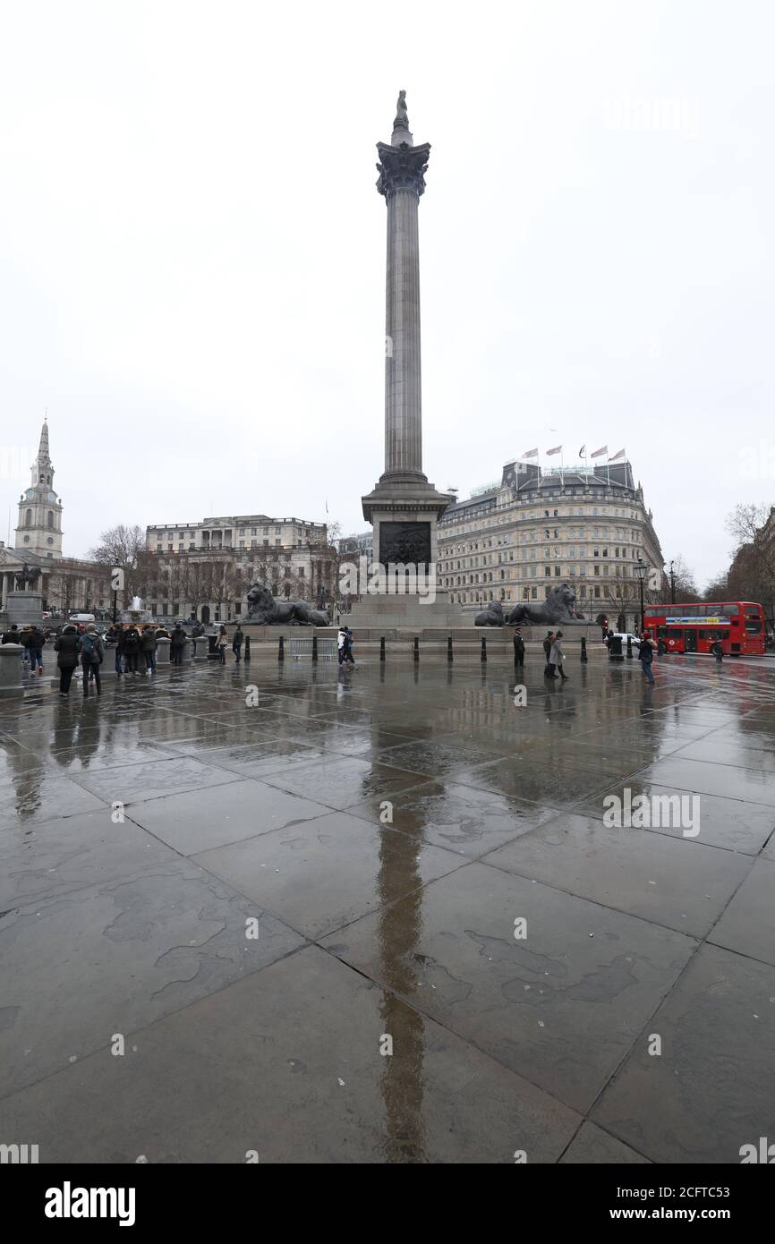 Reflet de la colonne de Nelson vue sur la dalle de Trafalgar Square lors d'un jour pluvieux à Londres. Banque D'Images