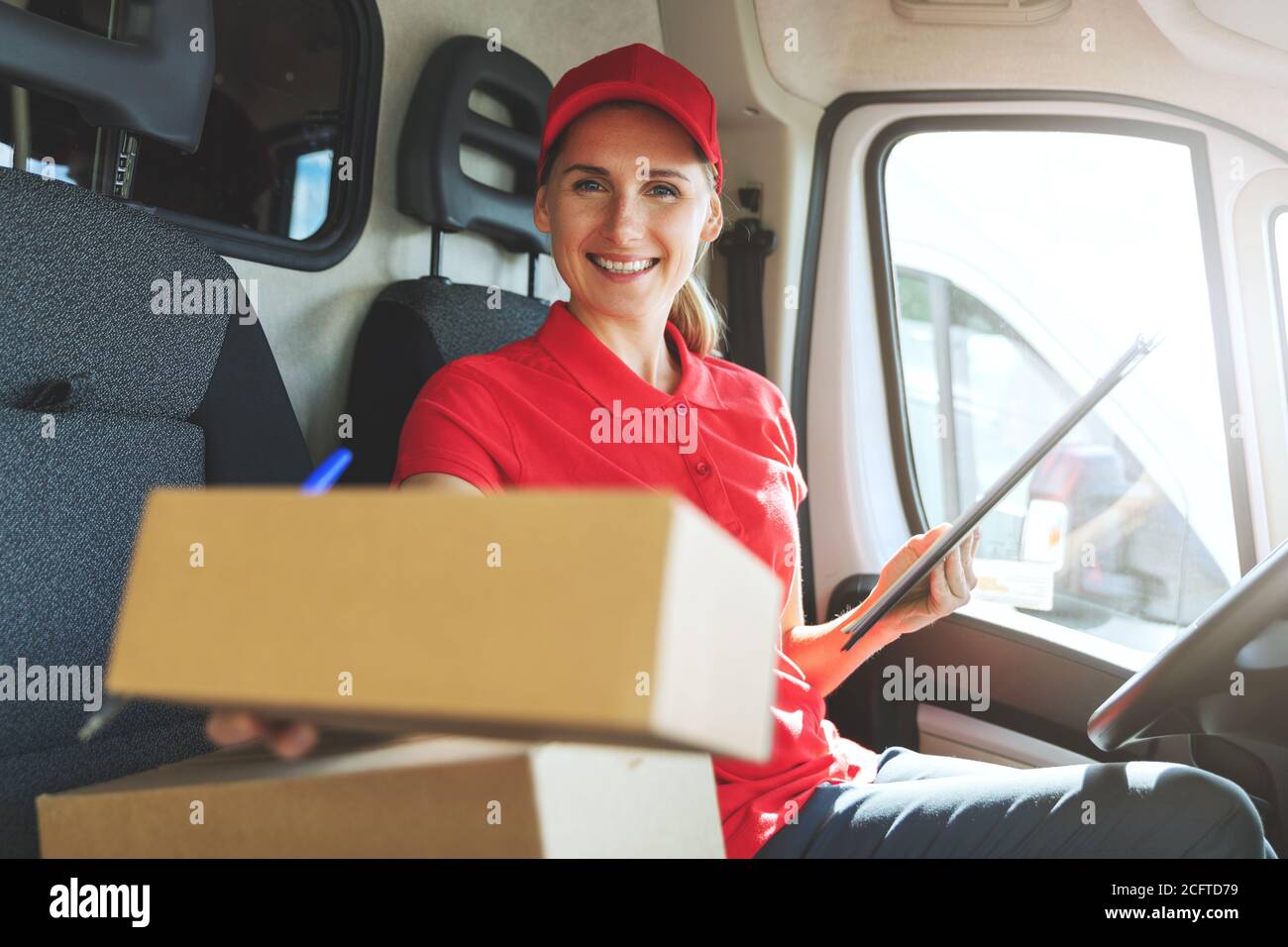 jeune femme heureuse employée de service de livraison assis dans une camionnette et livraison d'une boîte Banque D'Images