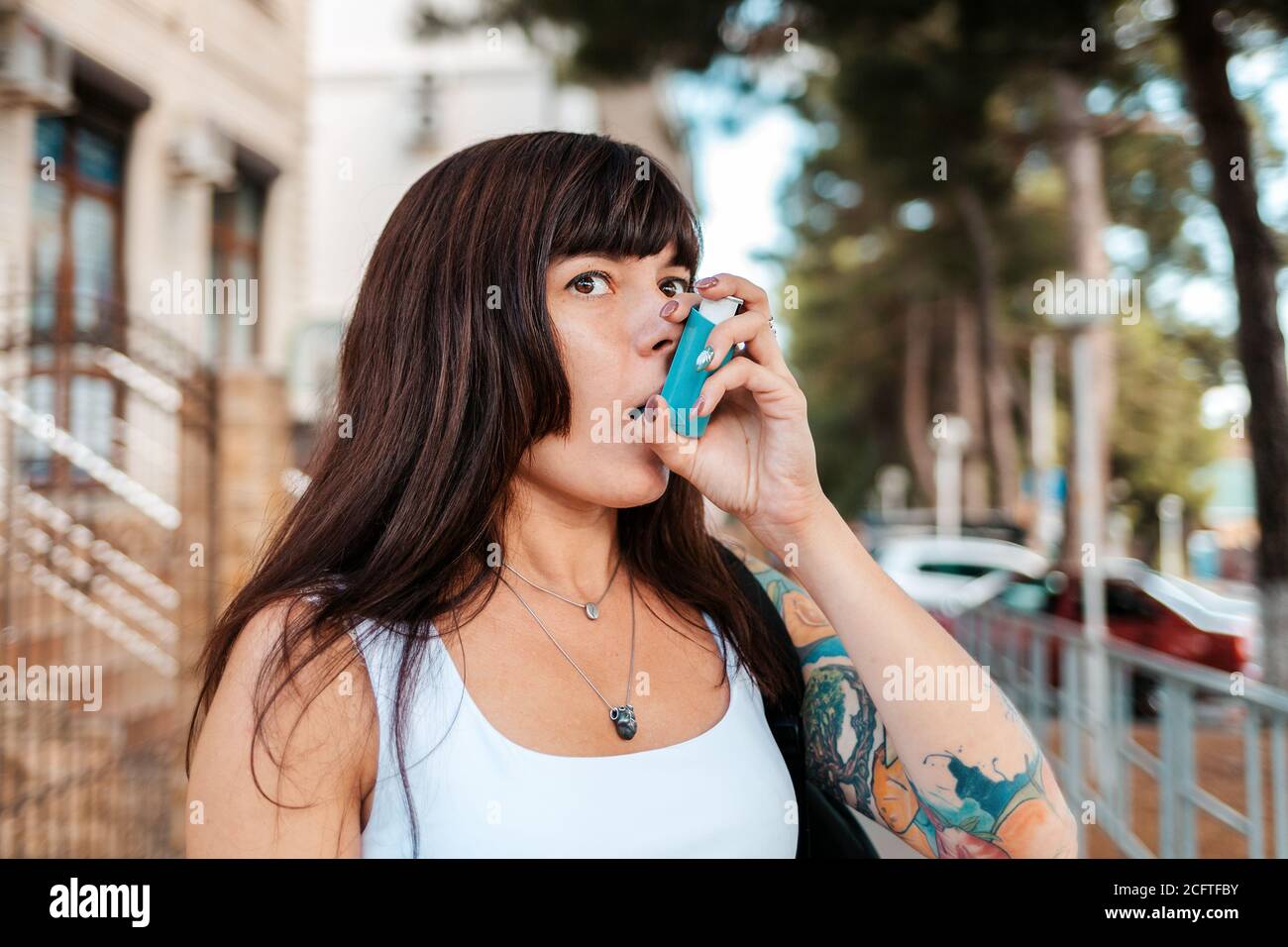 Une femme avec un tatouage sur son bras, inhalant des médicaments d'un inhalateur. Le concept de l'asthme. Banque D'Images