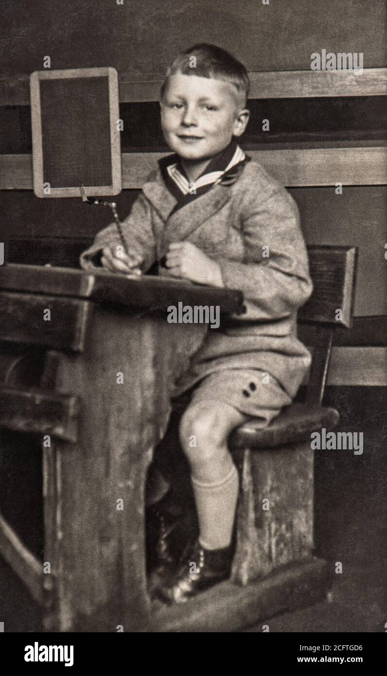 Garçon d'école dans la salle de classe. Photo vintage avec grain original, flou et rayures de env. 1939 Banque D'Images