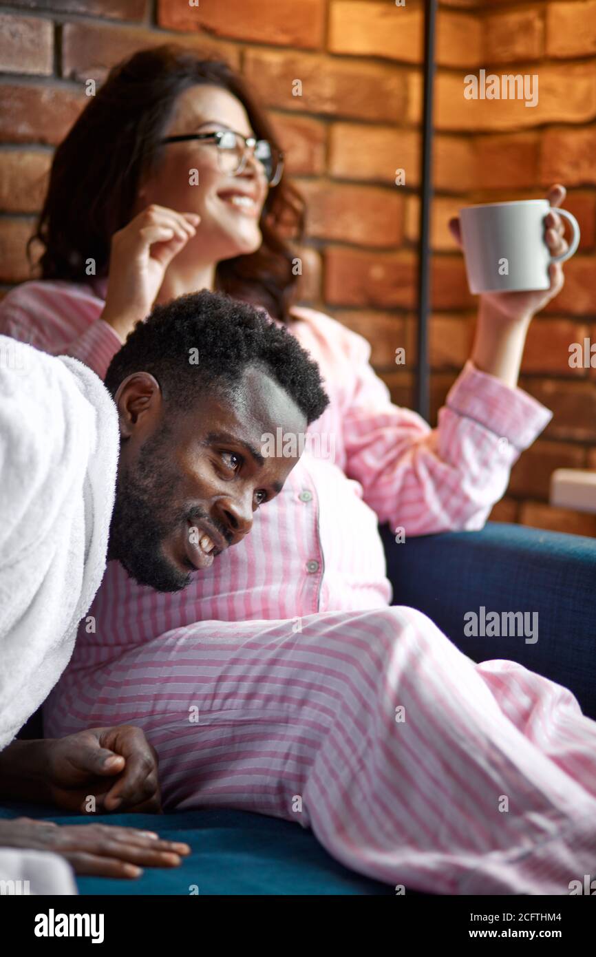 Je peux vous entendre. Heureux père africain mettant l'oreille à la femme ventre et souriant, attendez-vous à bébé Banque D'Images