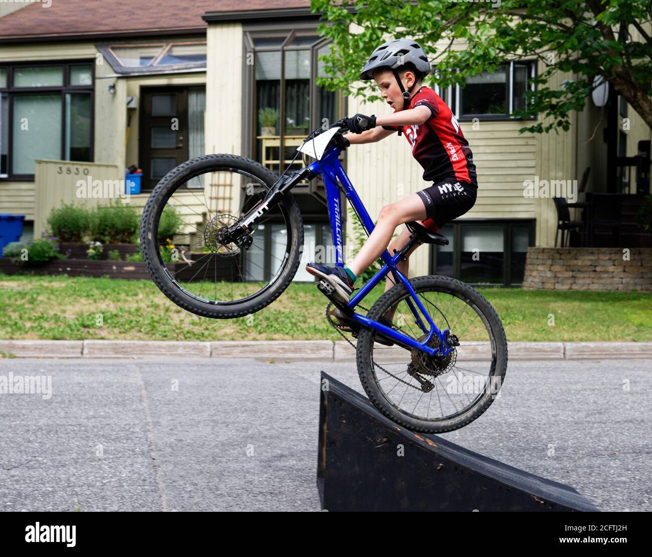 Un jeune garçon (8 ans) faire un grand saut sur son vélo de montagne Banque D'Images