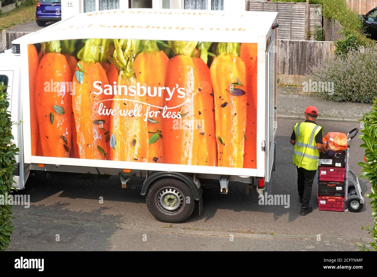Sainsburys supermarché livraison de fourgon garé vue aérienne conducteur empilement nourriture sur le chariot de la commande en ligne de shopping à la maison Essex Royaume-Uni Banque D'Images
