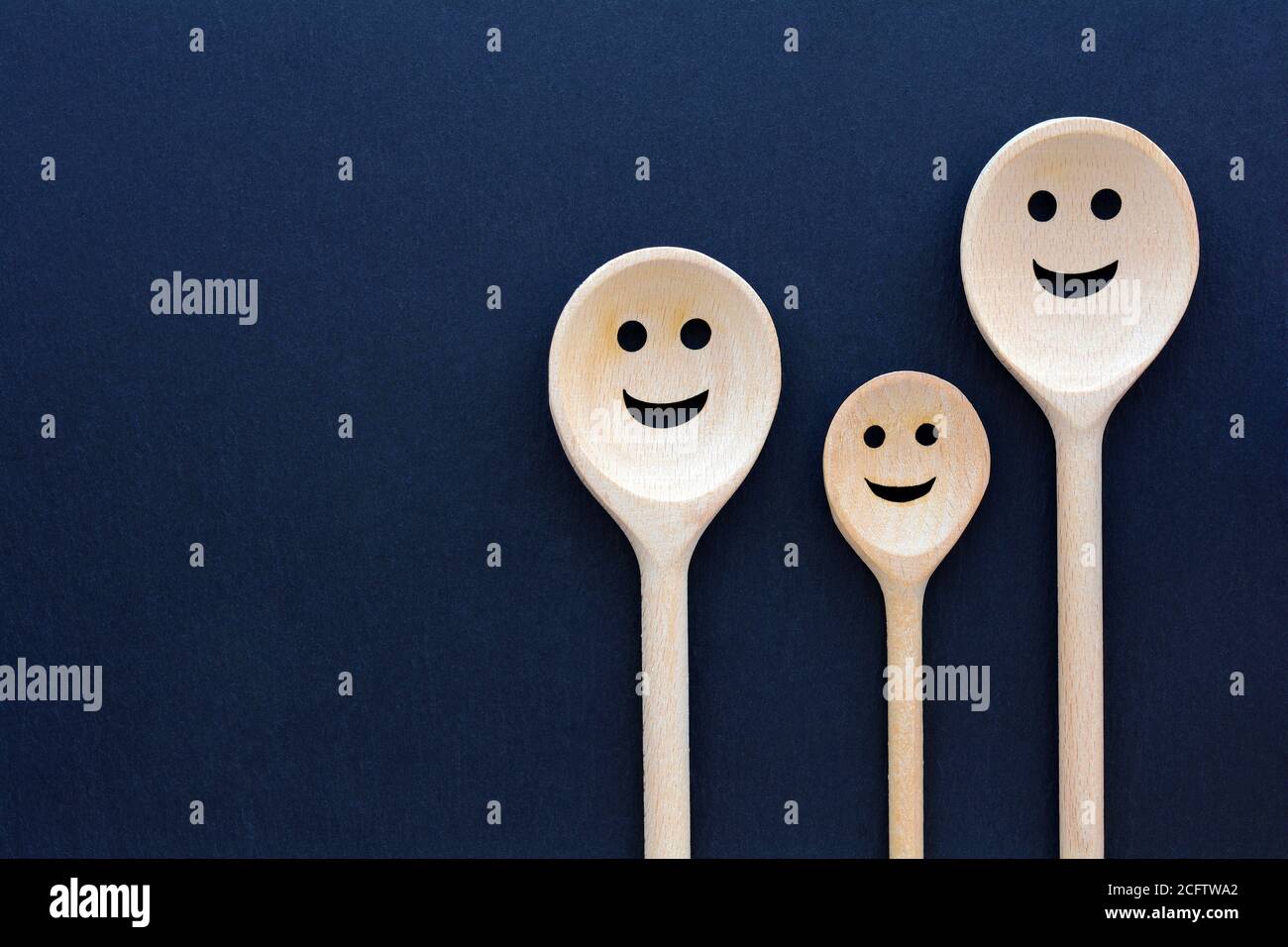 Les cuillères en bois ressemblent à une famille heureuse. Visages souriants. Banque D'Images