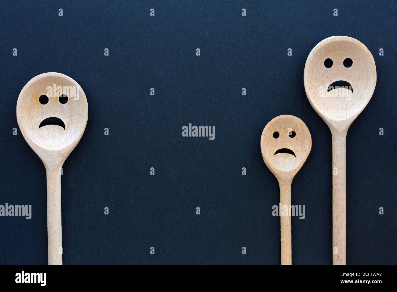 Les cuillères en bois ressemblent à une famille triste. Des visages sordides Banque D'Images