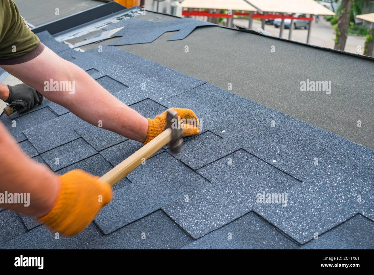 Les ouvriers installent les bardeaux de toit en bitume à l'aide d'un  marteau dans les clous Photo Stock - Alamy