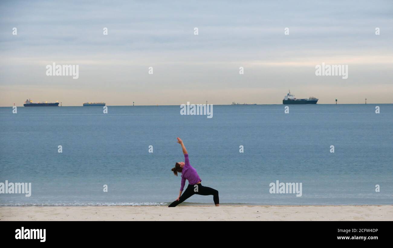 Melbourne Australie. Scènes de la vie quotidienne à Melbourne en Australie. Une femme faisant du yoga sur la plage de Port Phillip Bay. Banque D'Images