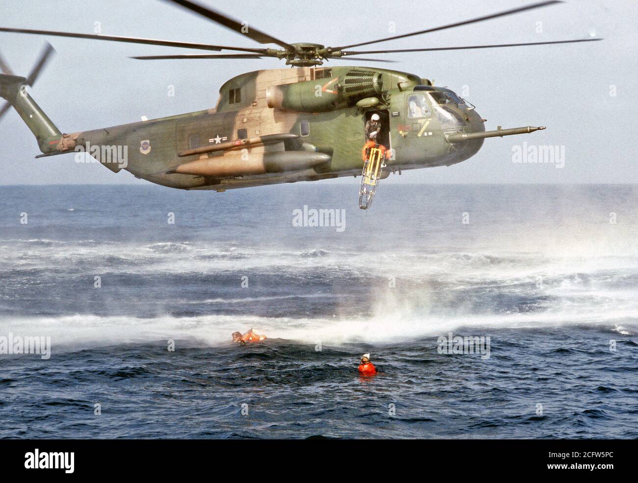 1978 - une litière est largué d'un hélicoptère en vol stationnaire HH-53 à pararescuemen du 55e Escadron de sauvetage et de récupération de l'aérospatiale, Eglin AFB, en Floride, comme ils aident un "survivant" flottant dans l'eau. L'exercice de sauvetage en mer est organisé pour un film production. Banque D'Images