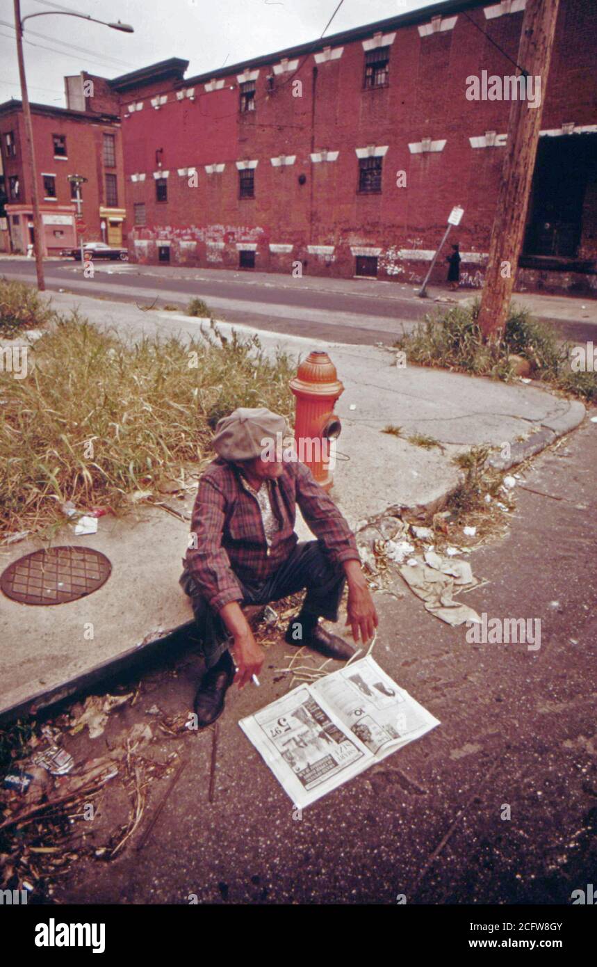 Homme tuer le temps dans le nord de Philadelphie, Août 1973 Séance sur route trottoir Banque D'Images