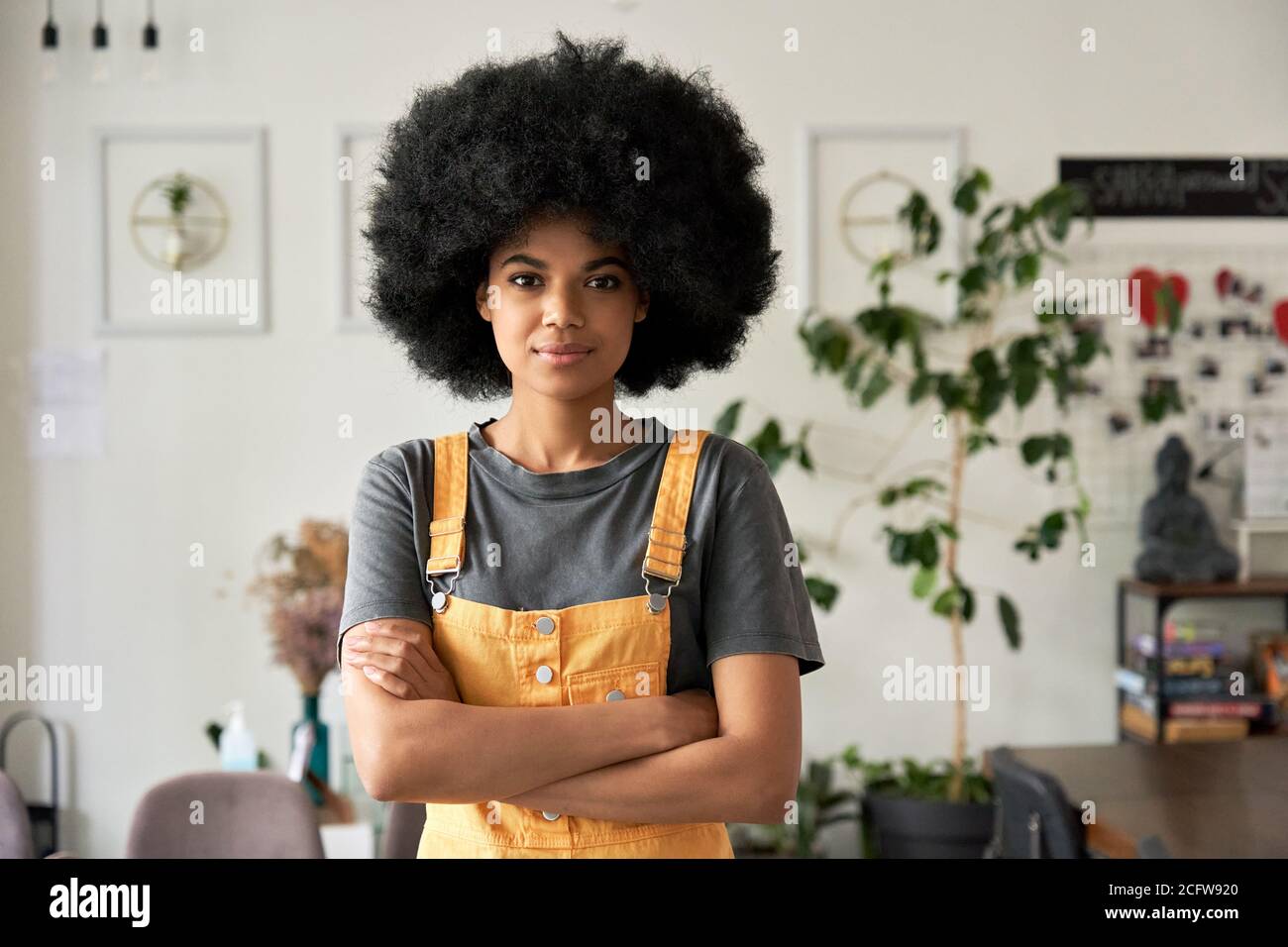 Une femme africaine confiante avec des cheveux afro regarde des stands d'appareil photo dans un café, portrait. Banque D'Images