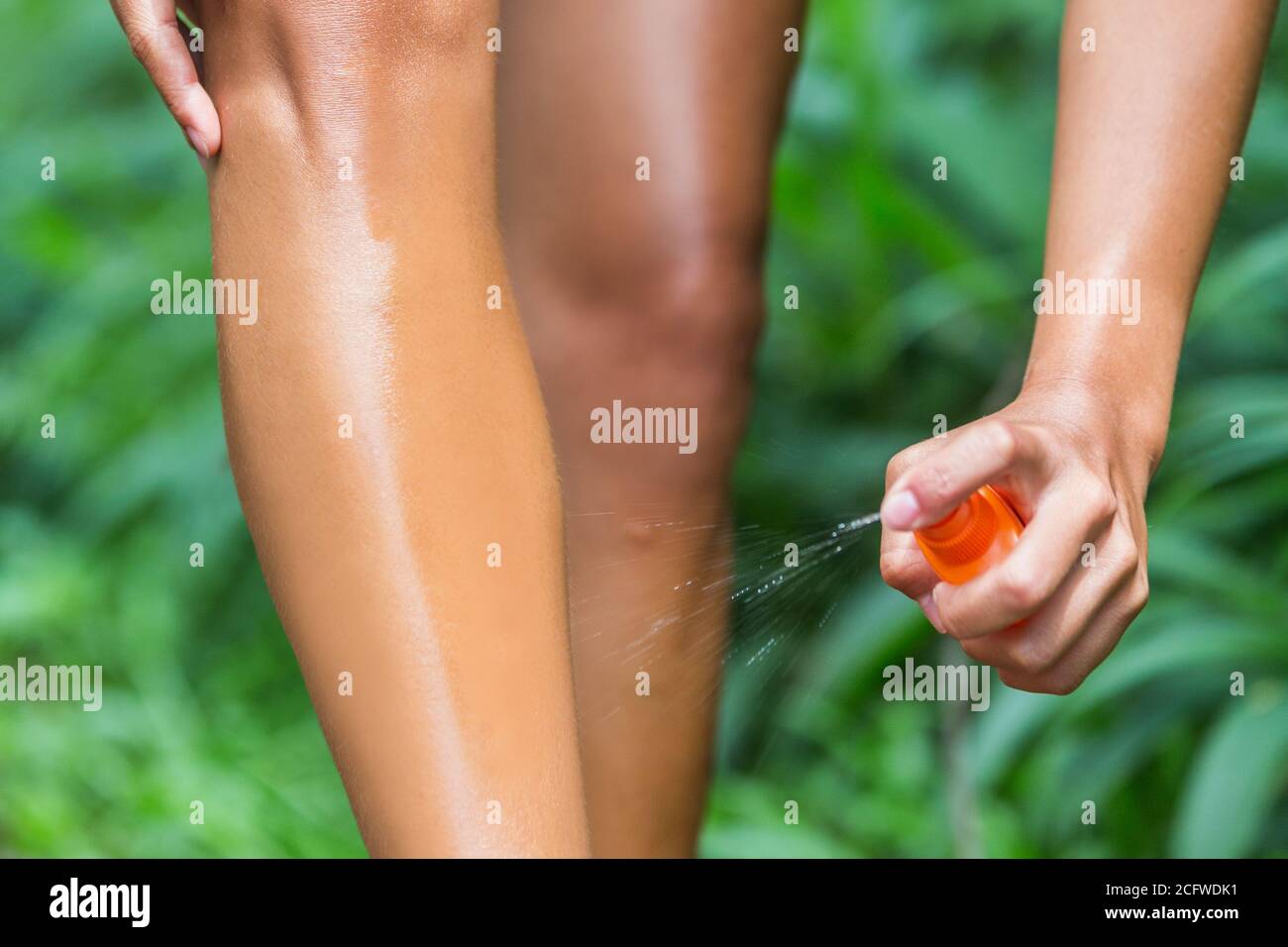 Femme pulvérisant un produit anti-moustiques sur la peau des jambes. Femme utilisant une bouteille anti-insectes anti-insectes sur les jambes, le corps et les vêtements en plein air dans la forêt naturelle Banque D'Images