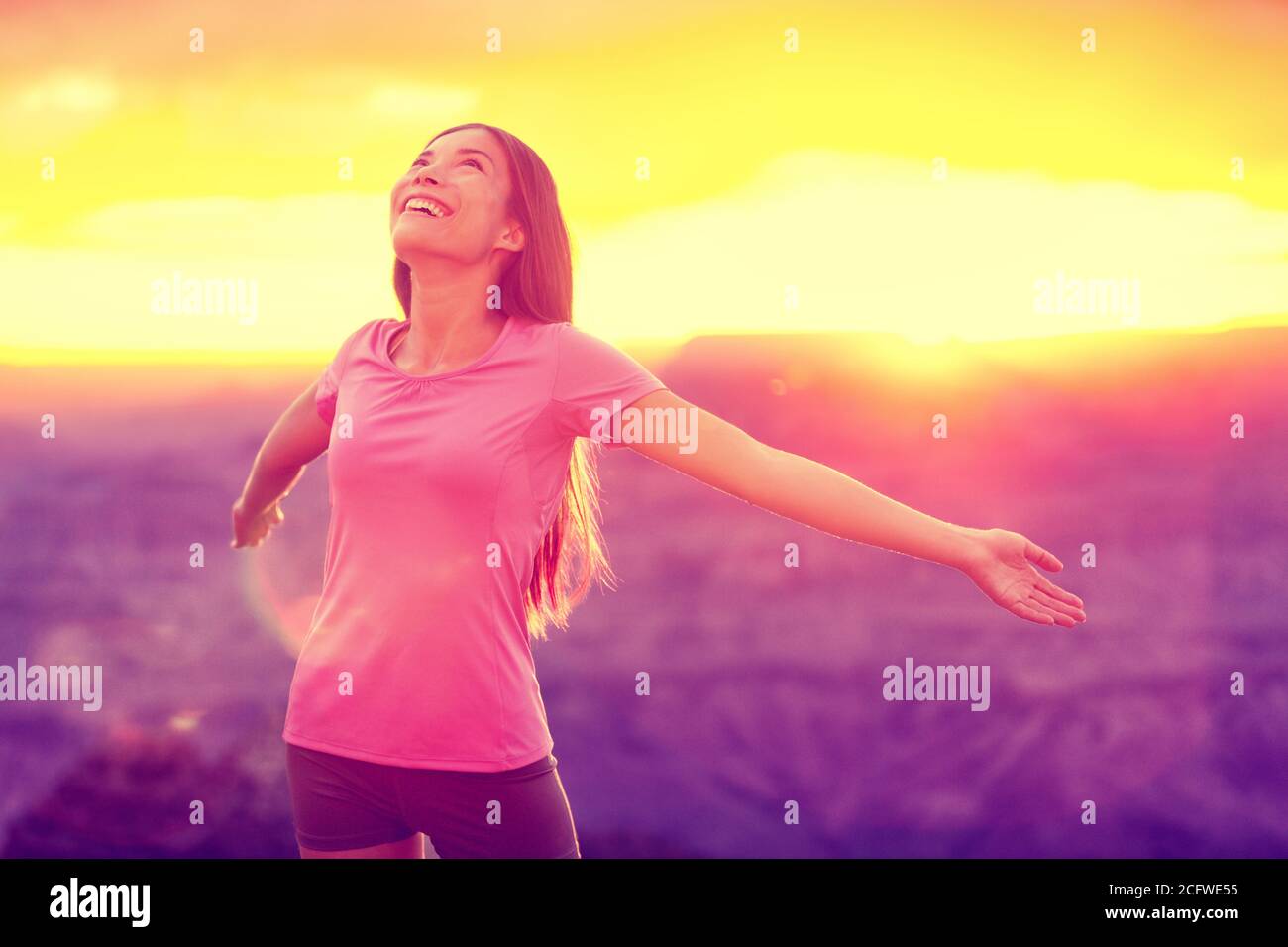 Femme heureuse gratuite profitant du coucher de soleil sur la nature. Concept de liberté, de bonheur et de plaisir de jeune fille asiatique multiraciale aux armes ouvertes dans l'espoir et Banque D'Images