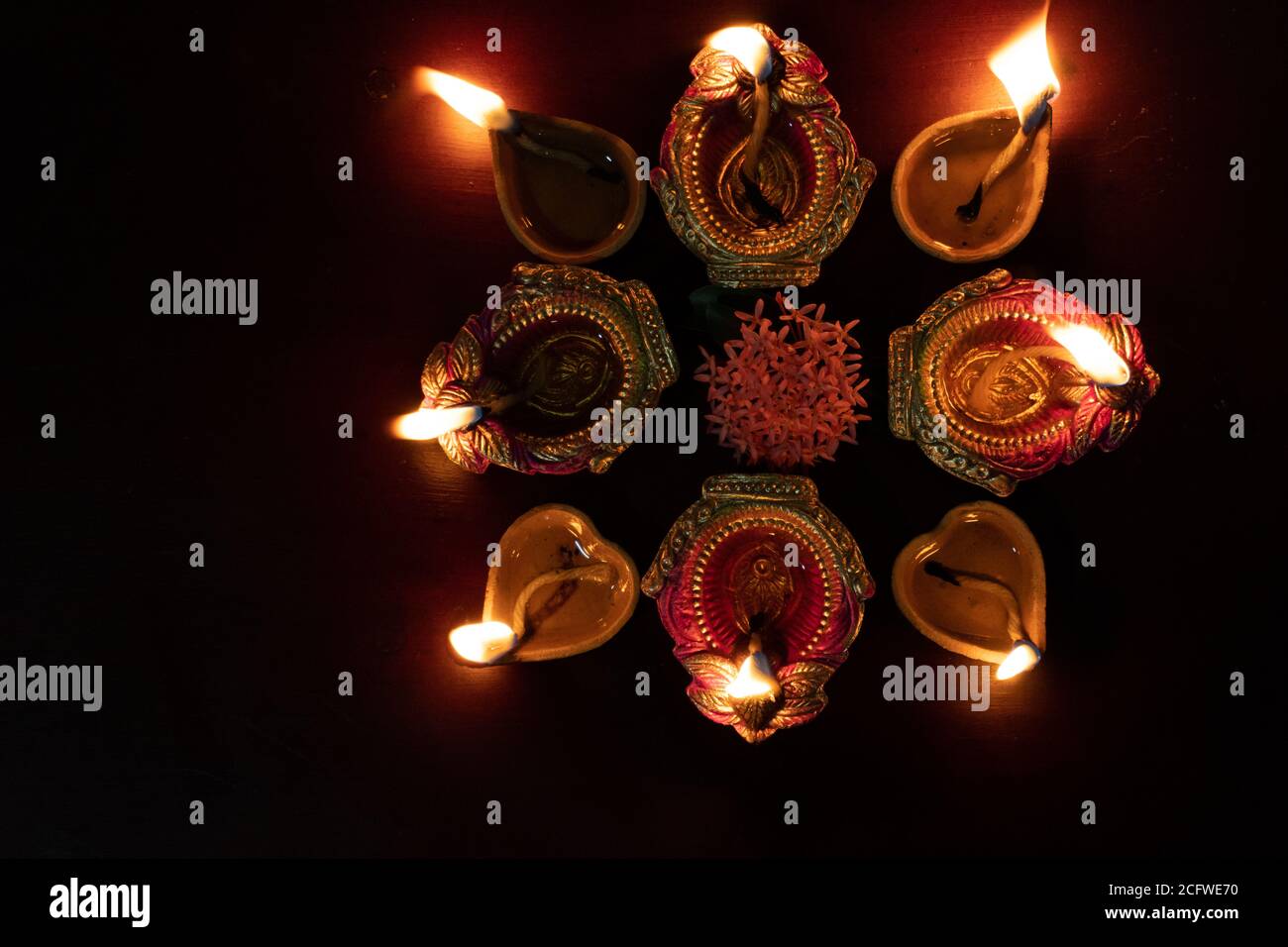 Lampes à huile Diwali colorées, lampes à huile Deepavali illuminées en belle formation avec des fleurs au milieu. Banque D'Images