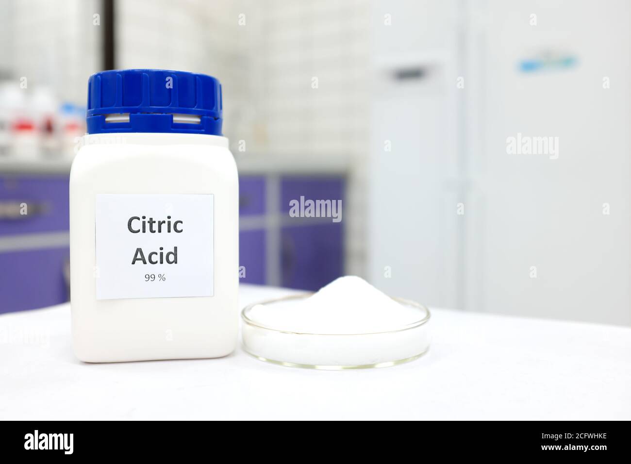 Foyer sélectif d'une bouteille d'acide citrique à côté d'une boîte de Petri avec une substance en poudre cristalline blanche. Fond blanc de laboratoire avec espace de copie. Banque D'Images