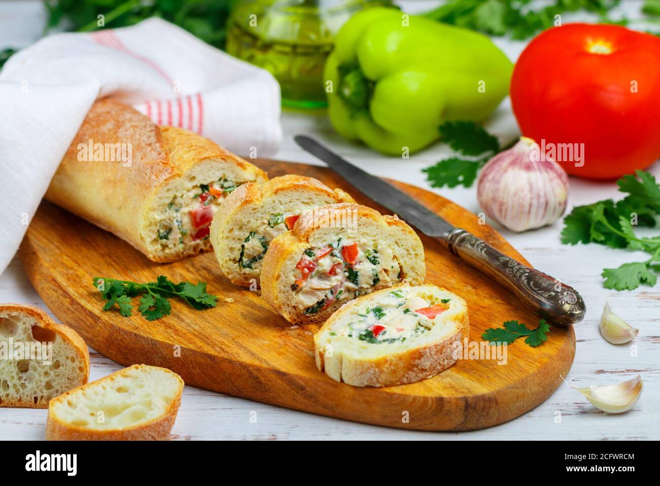 Baguette farcie avec une salade de poulet cuit, fromage et légumes frais - poivron, tomate, ail, persil. Délicieux hors-d'œuvre maison pour gou Banque D'Images