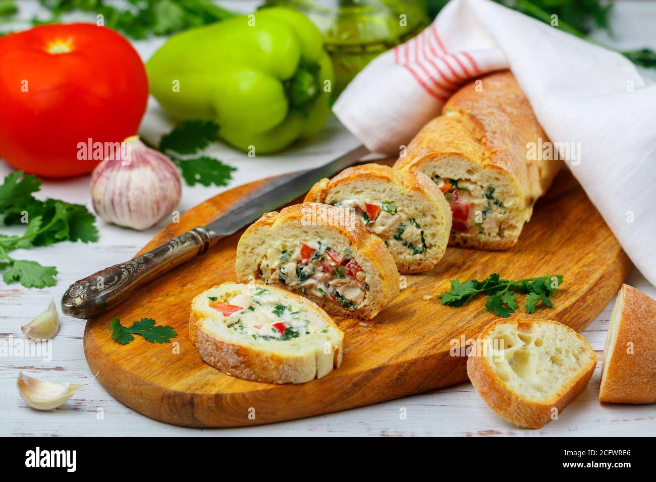 Baguette farcie avec une salade de poulet cuit, fromage et légumes frais - poivron, tomate, ail, persil. Délicieux hors-d'œuvre maison pour gou Banque D'Images