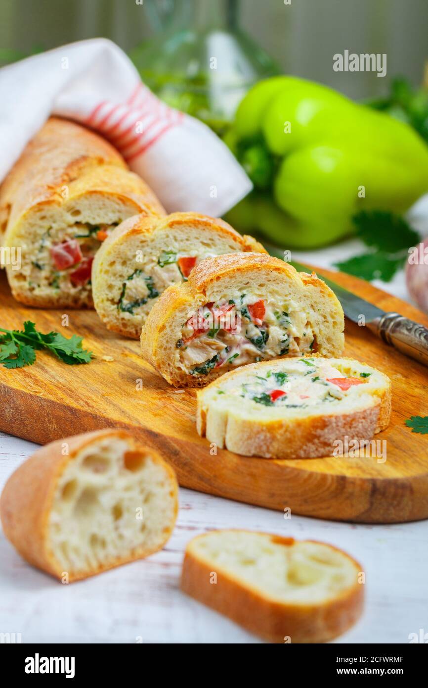 Baguette farcie avec une salade de poulet cuit, fromage et légumes frais - poivron, tomate, ail, persil. Délicieux hors-d'œuvre maison pour gou Banque D'Images