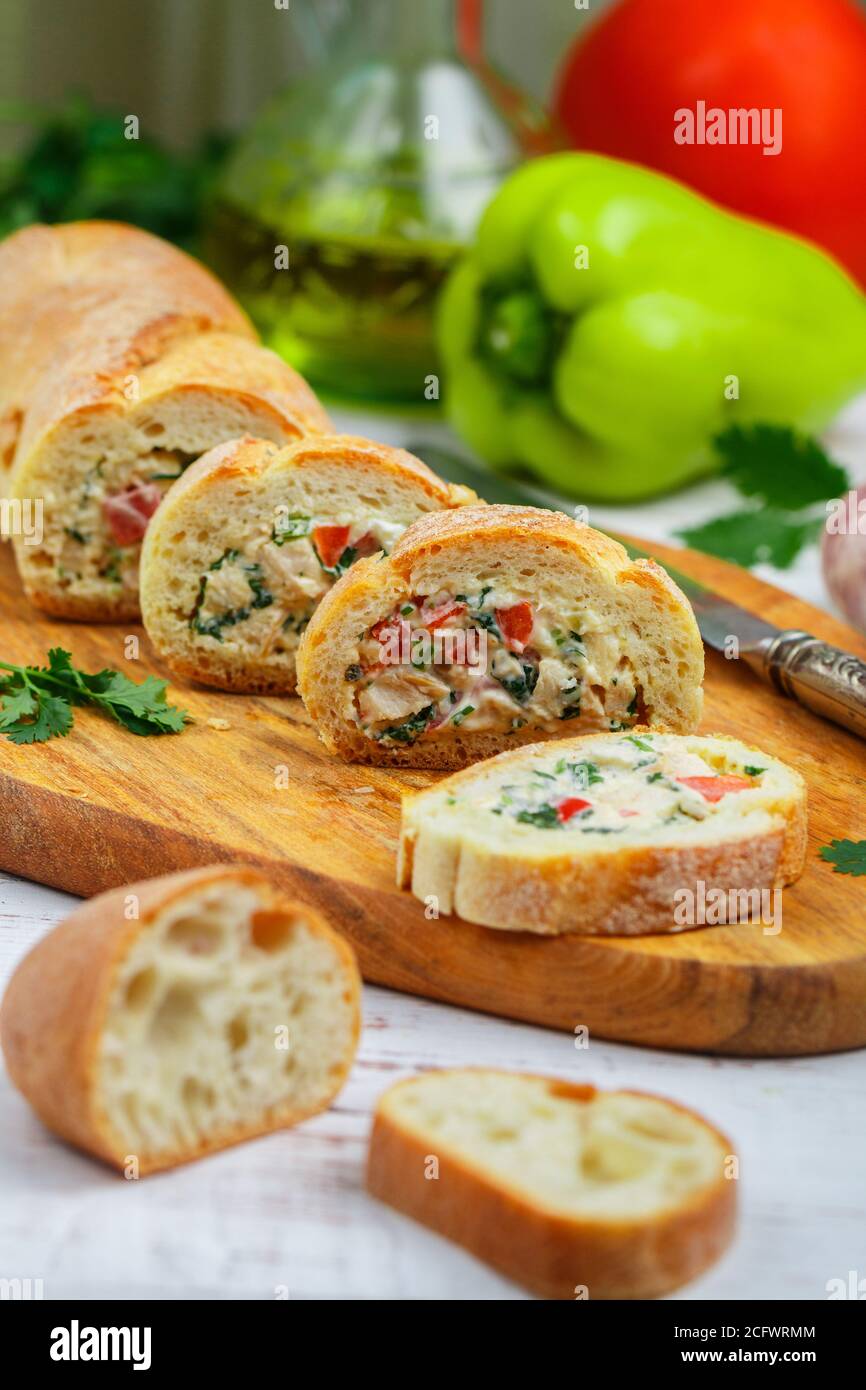 Baguette farcie avec une salade de poulet cuit, fromage et légumes frais - poivron, tomate, ail, persil. Délicieux hors-d'œuvre maison pour gou Banque D'Images