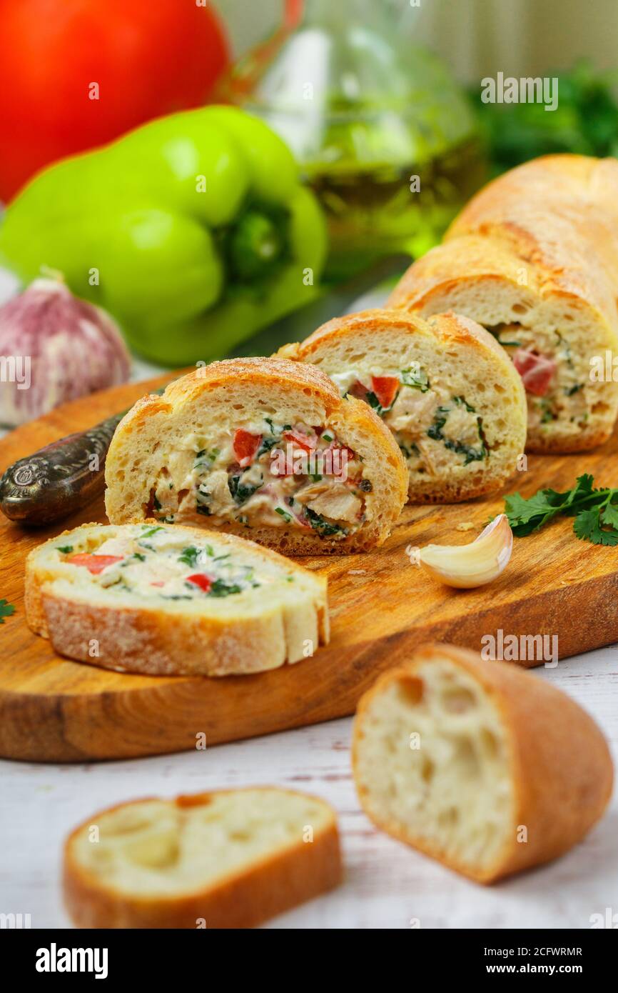 Baguette farcie avec une salade de poulet cuit, fromage et légumes frais - poivron, tomate, ail, persil. Délicieux hors-d'œuvre maison pour gou Banque D'Images