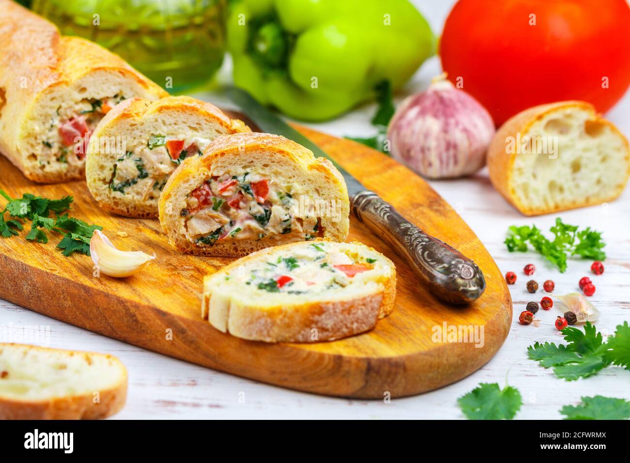 Baguette farcie avec une salade de poulet cuit, fromage et légumes frais - poivron, tomate, ail, persil. Délicieux hors-d'œuvre maison pour gou Banque D'Images