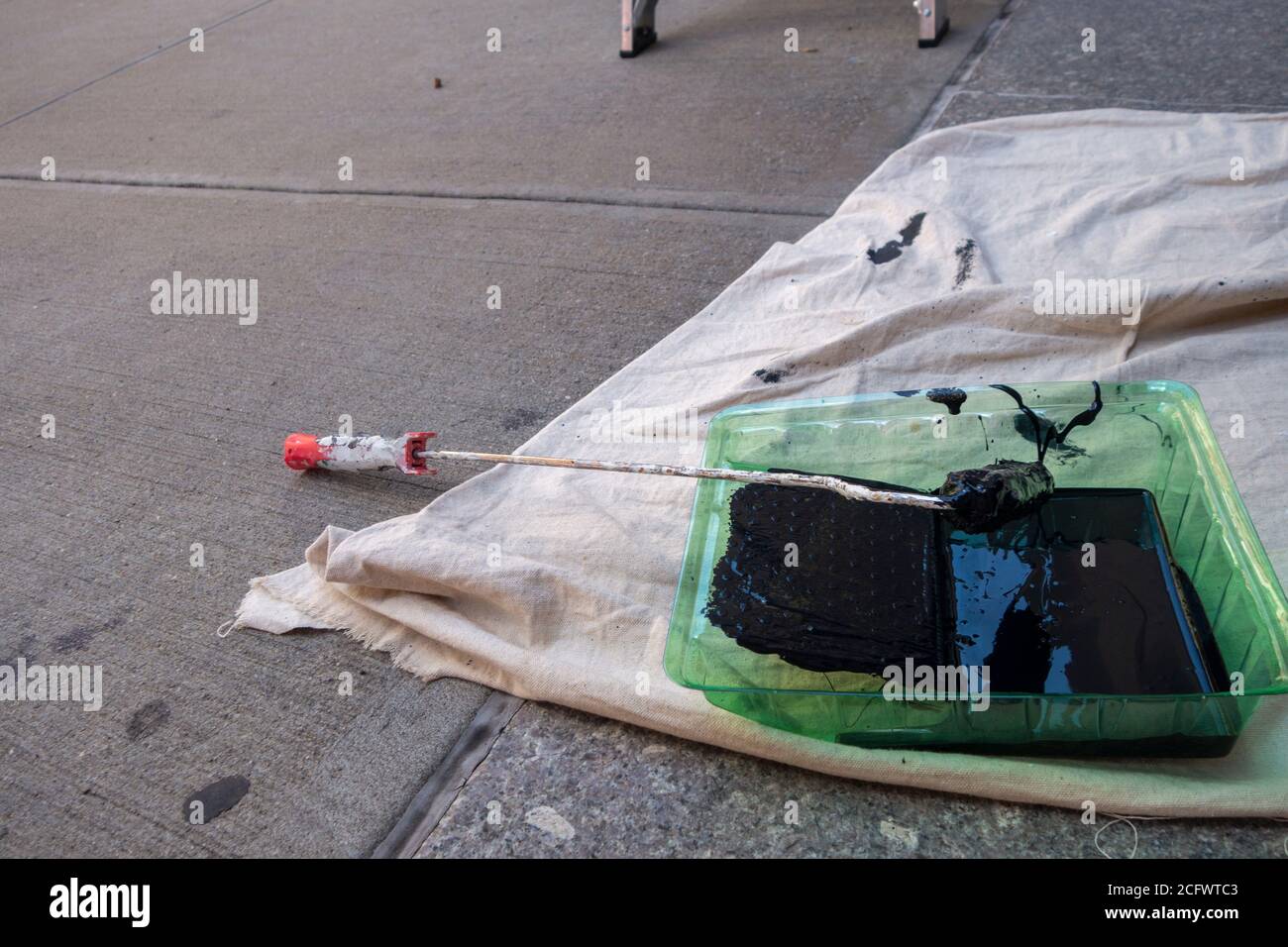 Peinture noire dans un plateau à rouleaux vert à l'extérieur peinture émaillée avec bâche abaissée Banque D'Images