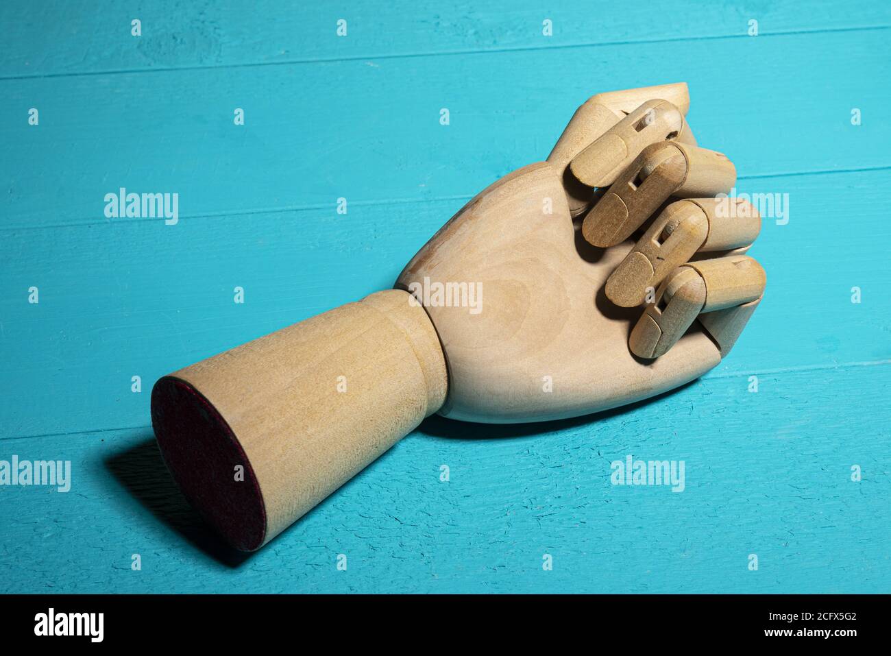 Une main en bois sur une table bleue Banque D'Images