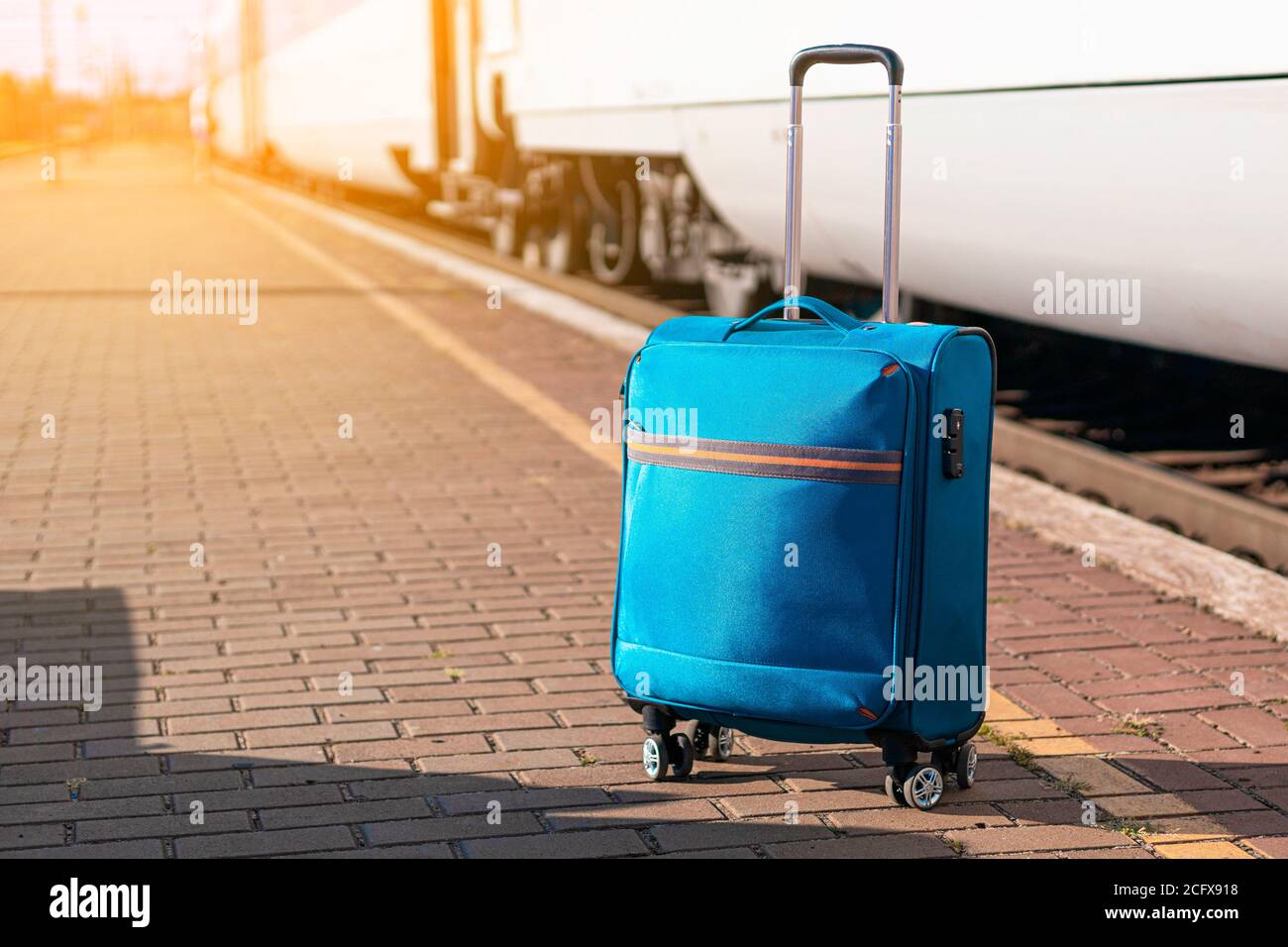 Valise à bagages bleue sur une plate-forme de chemin de fer gare près du  train par temps ensoleillé Photo Stock - Alamy