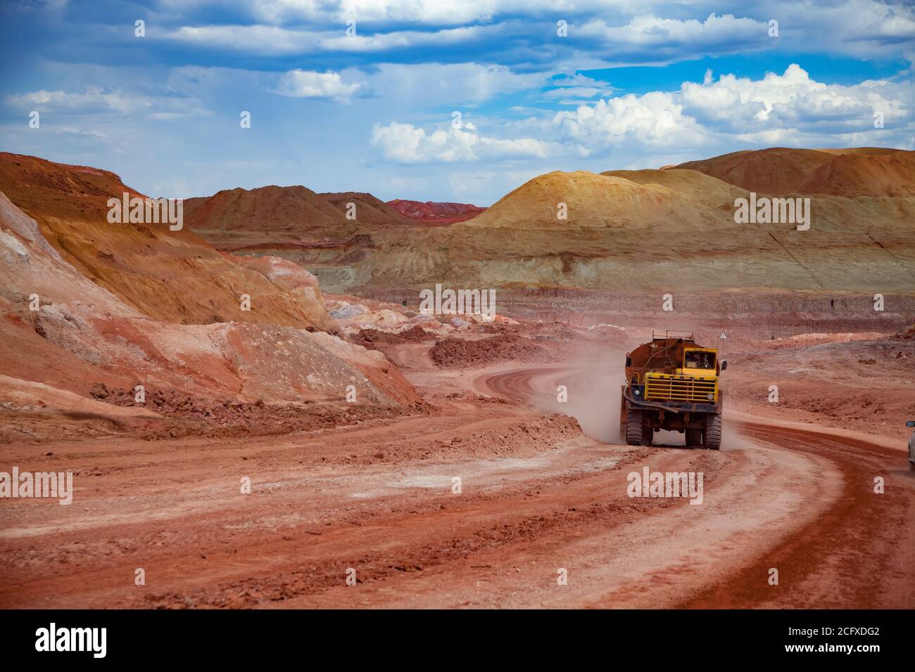 Exploitation et transport du minerai d'aluminium. Mine d'argile de bauxite. Tas de terrain vide. Camion « Belaz » sur une route en argile rouge. Ciel bleu et nuages. Banque D'Images