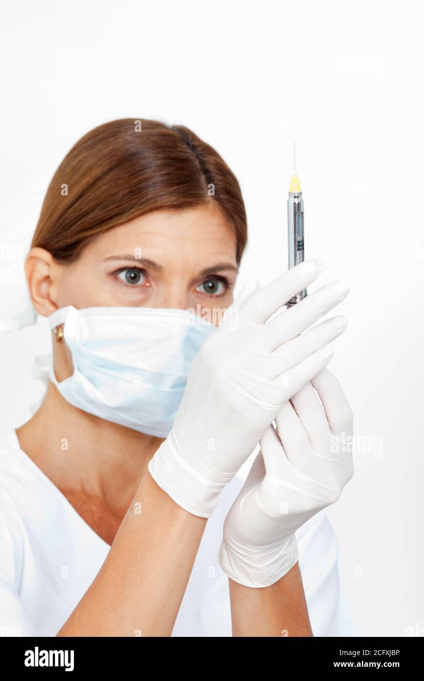 Le dentiste muni d'un masque tire une seringue Banque D'Images