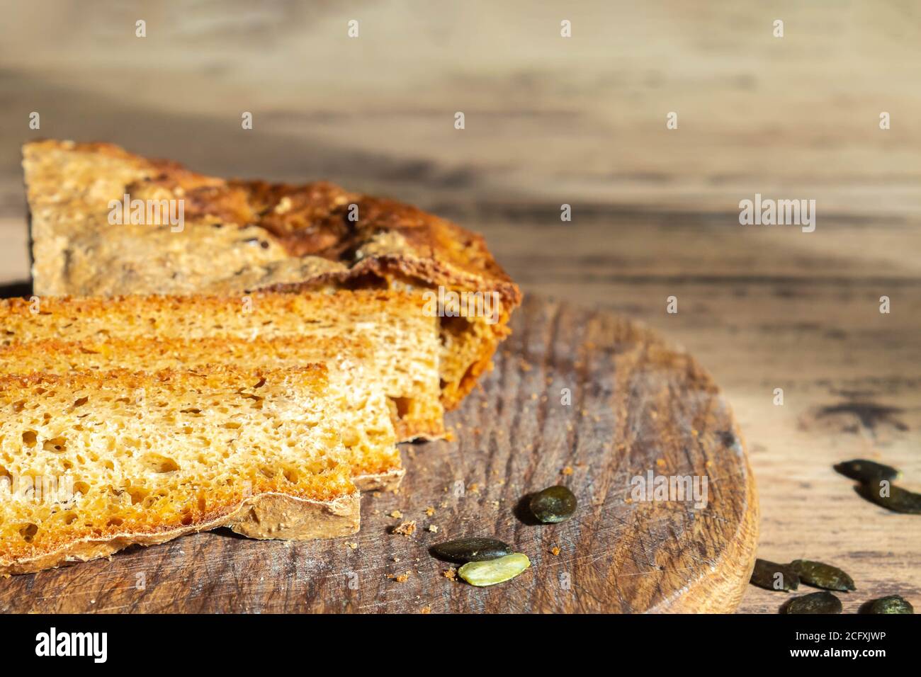 Du pain de citrouille frais et des graines sur la planche à découper en gros plan. Pain de citrouille fait maison sur une table rustique en bois. Concept de fabrication de pain à domicile Banque D'Images