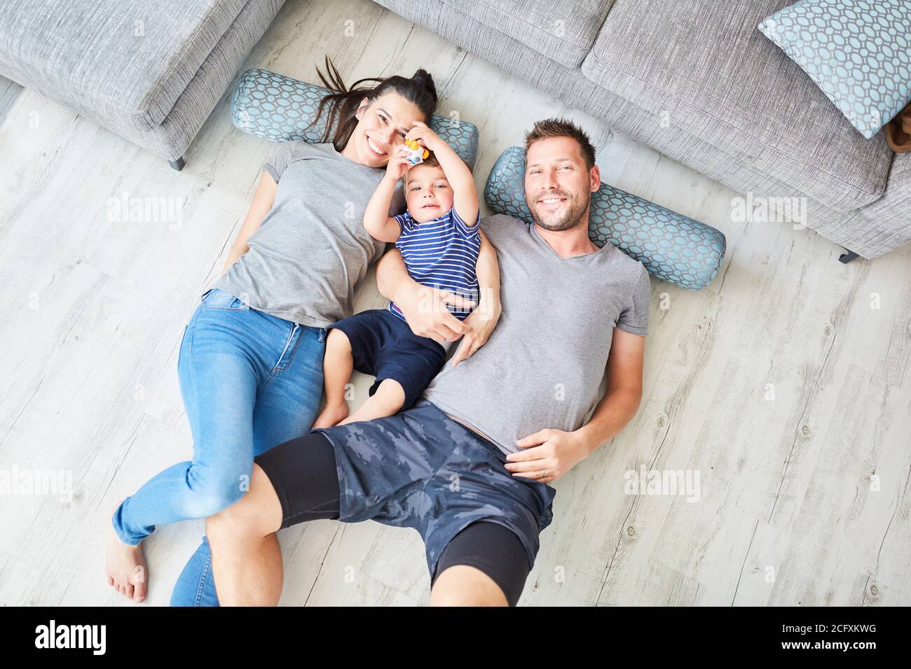 Les parents et les enfants se trouvent sur le sol dans la salle de séjour chambre en tant que petite famille heureuse Banque D'Images
