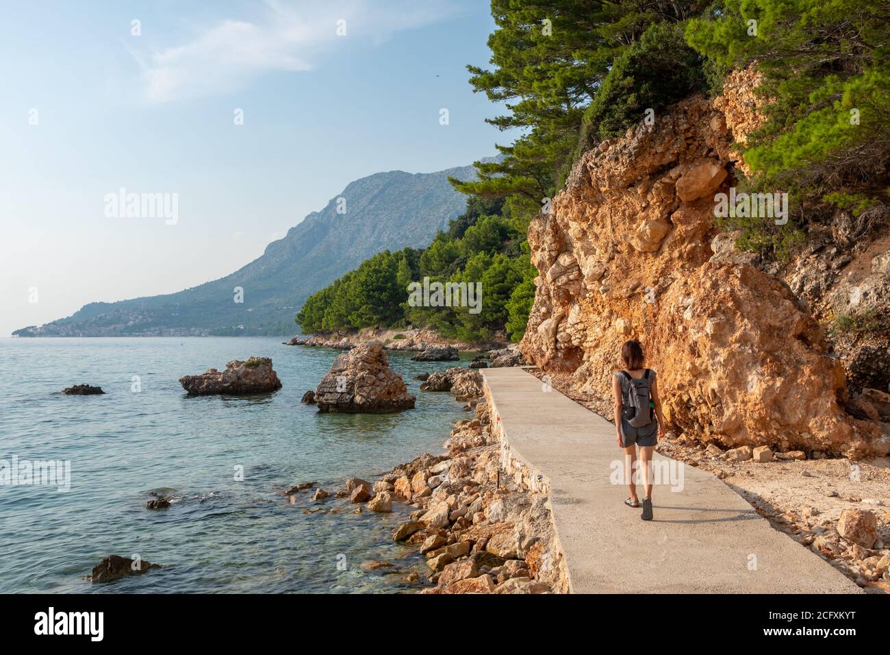 Une femme non identifiée marche sur la route touristique le long de la côte Adriatique de la Côte d'azur de Makarska, Croatie Banque D'Images