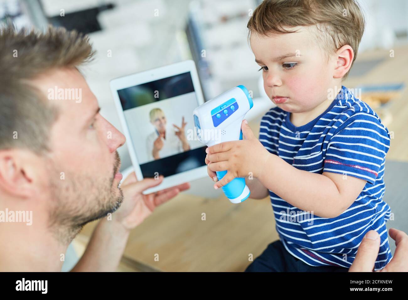 Père et enfant avec thermomètre clinique dans la consultation en ligne sur la tablette Banque D'Images