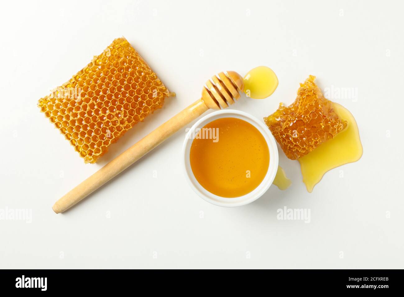Bol avec miel, balancier et nid d'abeille sur fond blanc Banque D'Images
