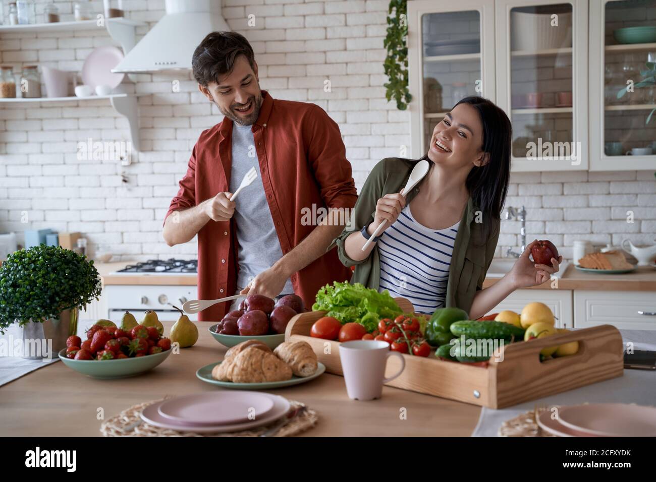 Cuisiner ensemble. Jeune famille heureux couple, femme et mari s'amuser  tout en préparant des aliments sains dans la cuisine moderne à la maison  Photo Stock - Alamy