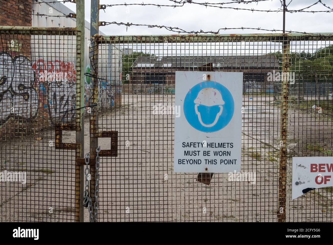 Panneau sur la clôture en fil de fer sur le chantier indiquant: Les casques de sécurité doivent être portés au-delà de ce point Banque D'Images