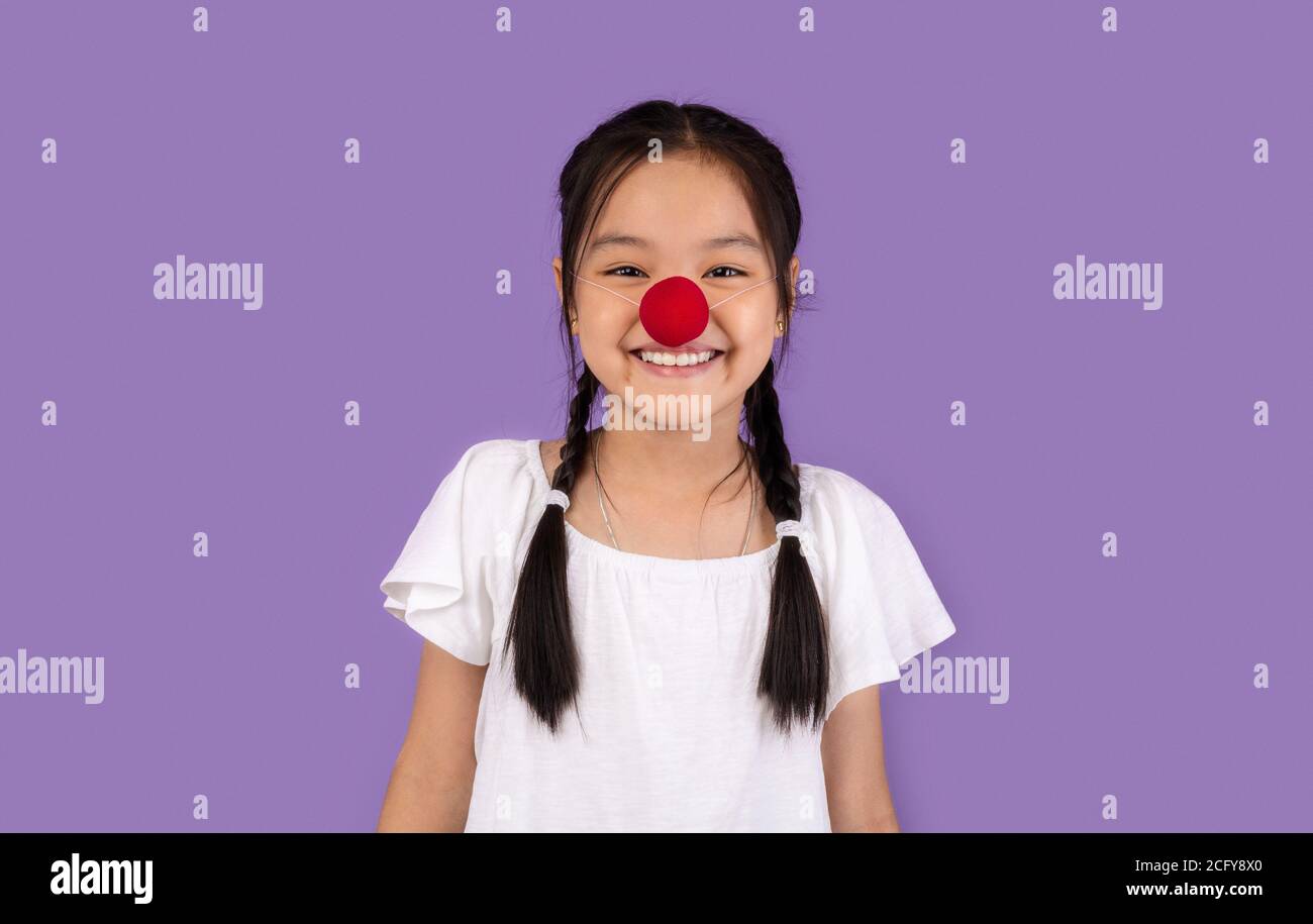 Drôle de Korean Kid Girl posant portant le nez de Clown, Studio Shot Banque D'Images