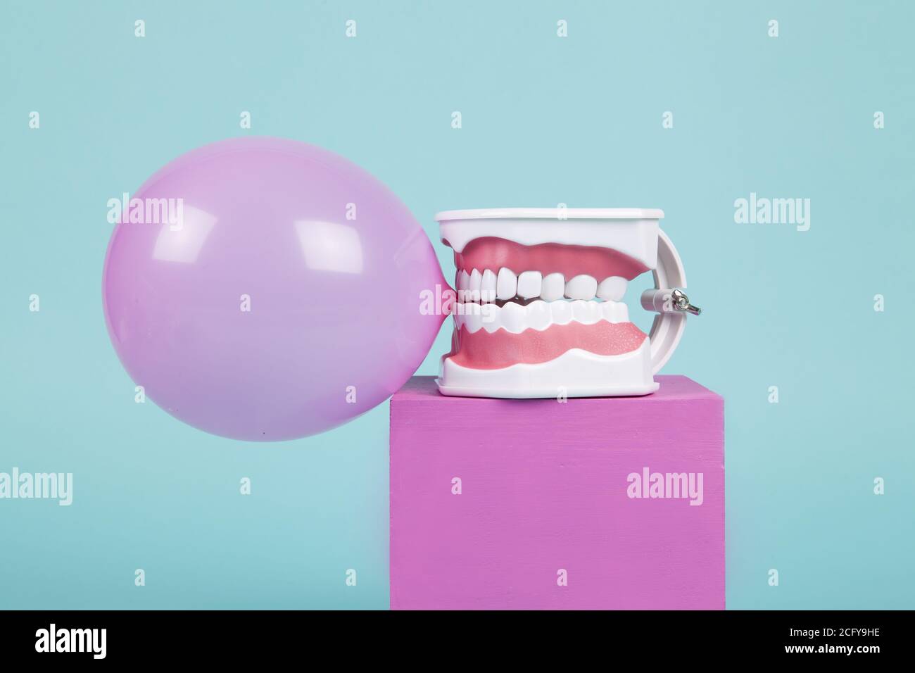 un modèle anatomique de dent en plastique pour apprendre à brosser les dents en tenant une boule de gomme à mâcher sur des cubes colorés. Humour et ambiance pop. Minimale Banque D'Images
