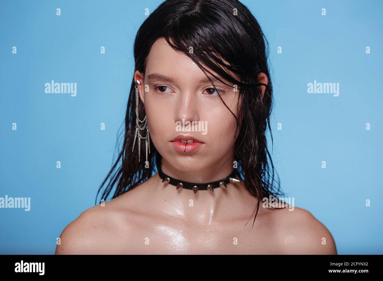 Portrait de belle femme gothique avec piercings et autres accessoires en studio sur fond bue. Émotif, jeune visage. Émotions humaines, exp. Facial Banque D'Images