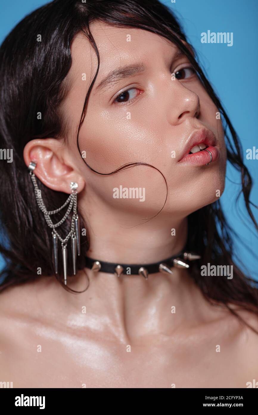 Portrait de belle femme gothique avec piercings et autres accessoires en studio sur fond bue. Émotif, jeune visage. Émotions humaines, exp. Facial Banque D'Images