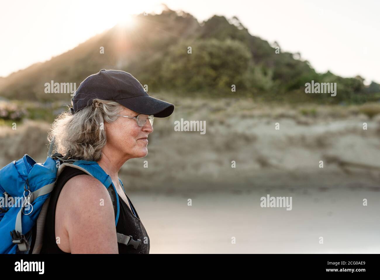 Femme active et âgée portant un sac à dos et un chapeau Une plage en Nouvelle-Zélande Banque D'Images