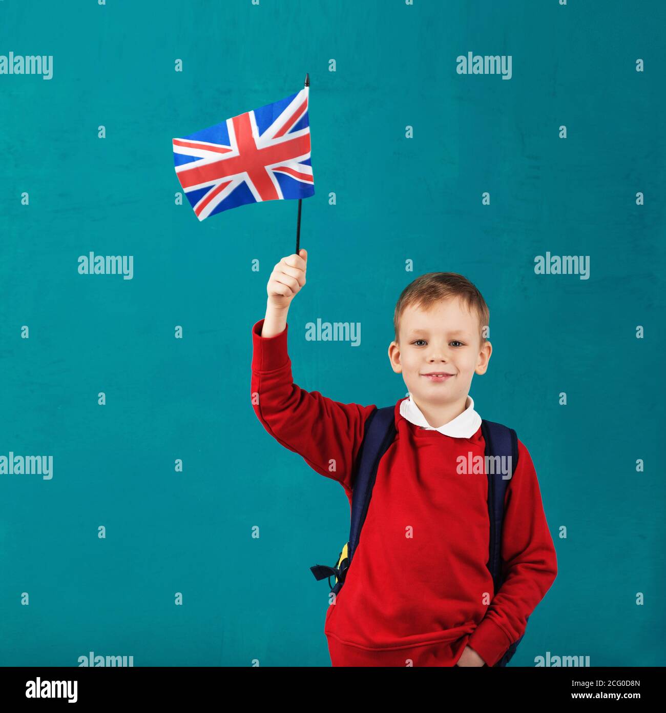 Vacances scolaires en Grande-Bretagne. Petit écolier avec le drapeau  national du Royaume-Uni ayant du plaisir contre le mur bleu. Anglais pour  enfants con Photo Stock - Alamy
