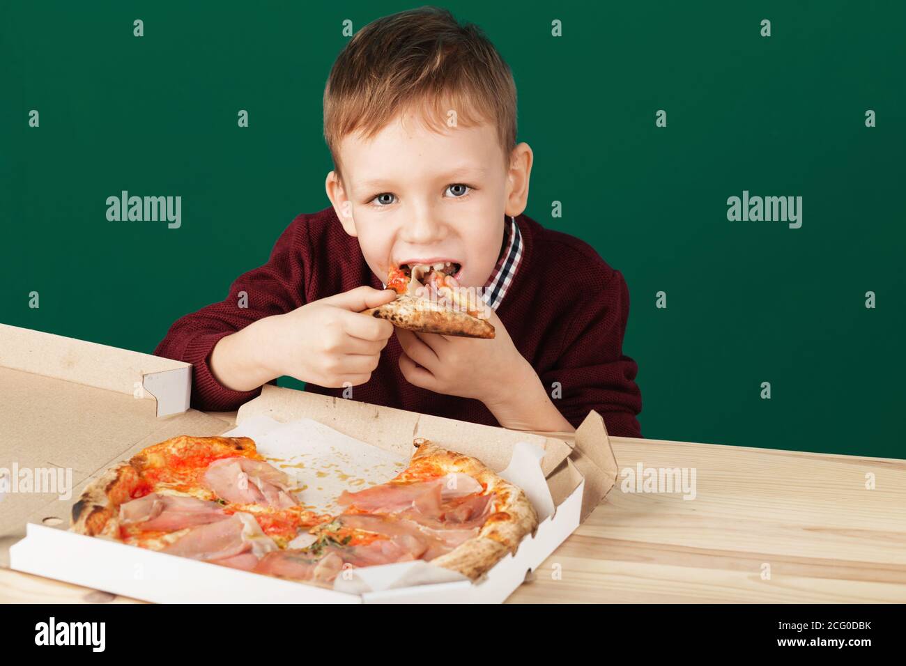 Les enfants mangent de la pizza italienne au café. Le garçon de l'école mange de la pizza pour le déjeuner. Concept de repas malsain pour enfant. Enfants affamés. Recette de pizza. Enfant mangeant pizz Banque D'Images