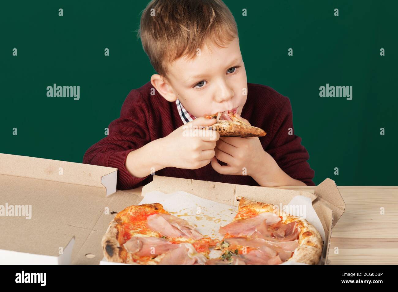 Les enfants mangent de la pizza italienne au café. Le garçon de l'école mange de la pizza pour le déjeuner. Concept de repas malsain pour enfant. Enfants affamés. Recette de pizza. Enfant mangeant pizz Banque D'Images